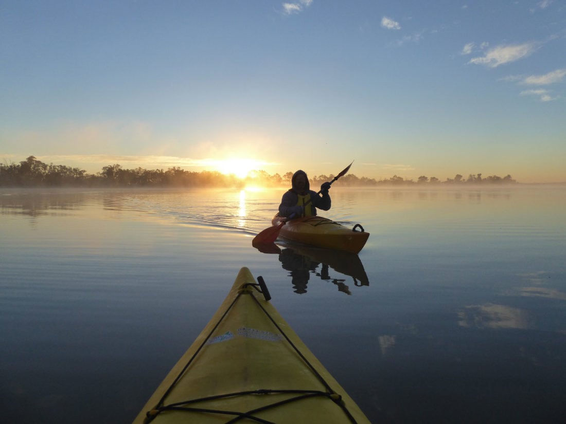 silhouette of kayaker in the mist, on the river in a golden sunrise
