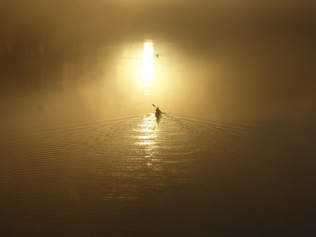 solitary kayaker on the water at sunrise - aerial view
