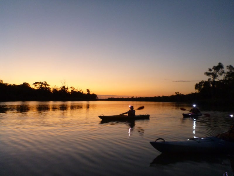 kayakers wearing head torches on th river after sunset